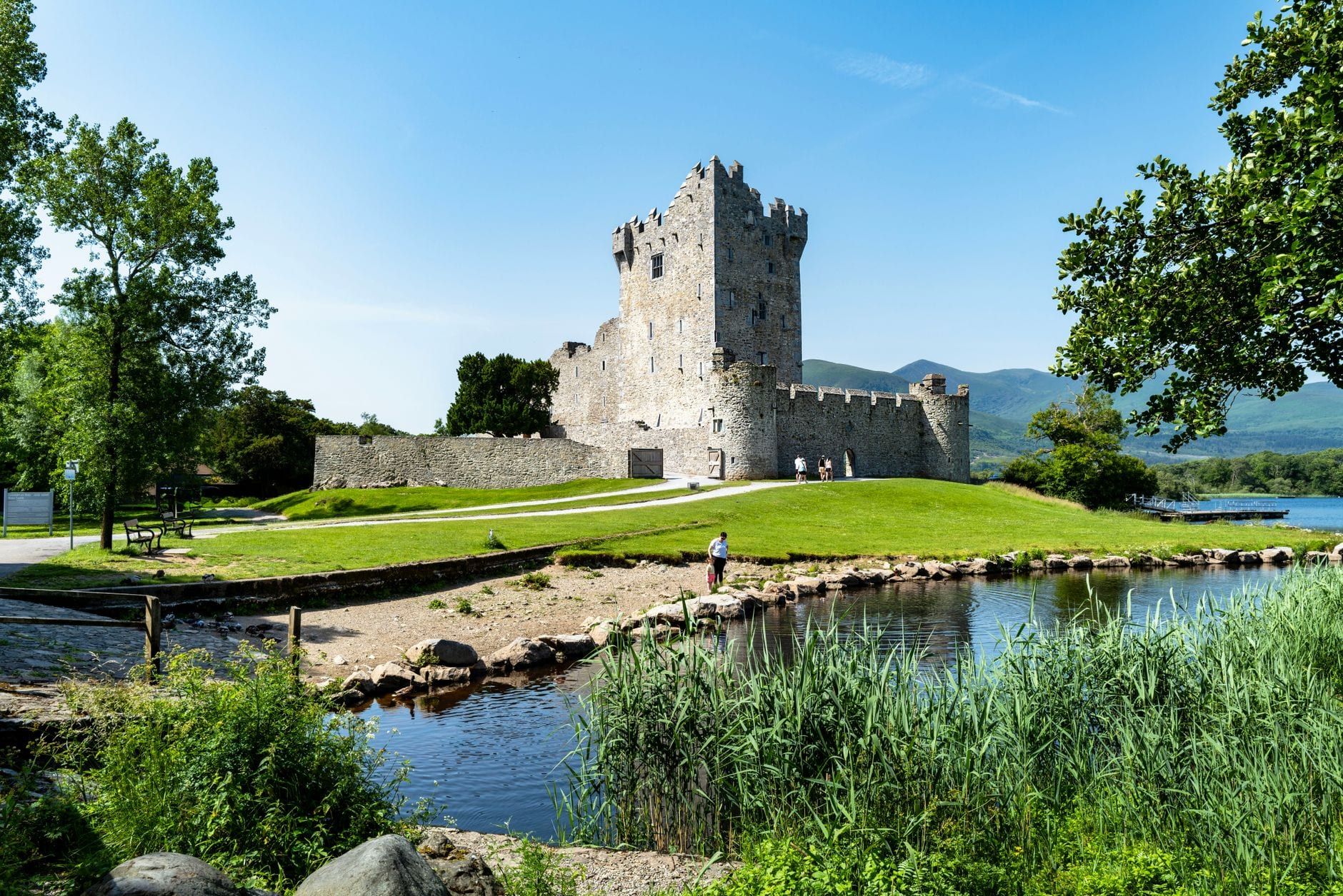 Ross Castle steht am Ufer des Lough Leane, umgeben von Bergen und üppigem Grün im Killarney Nationalpark.