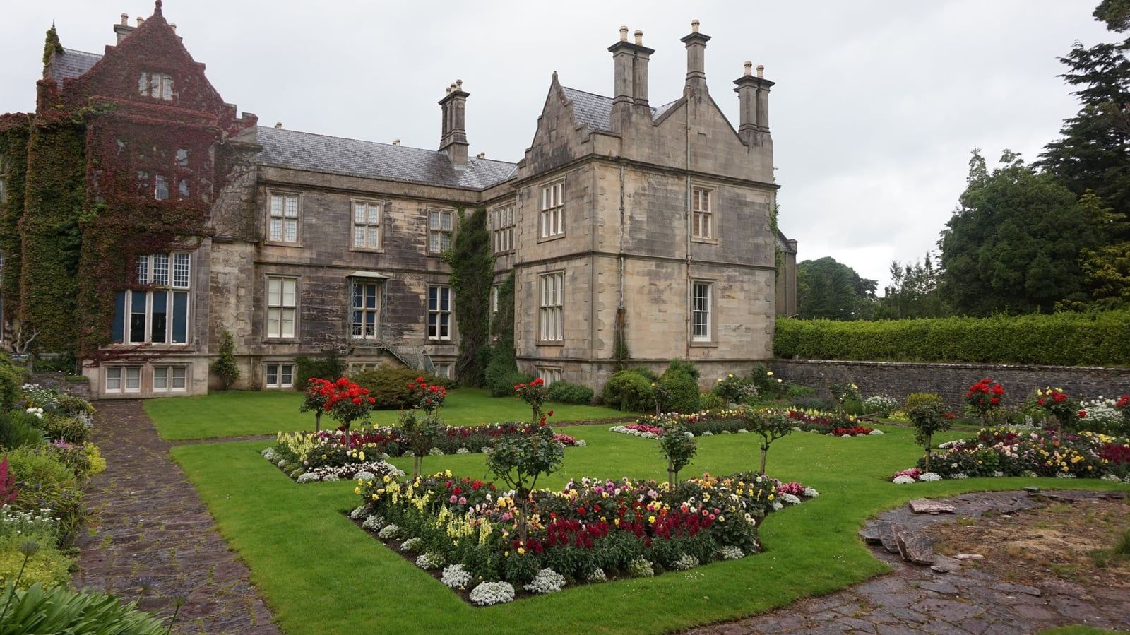 Gepflegte Blumenbeete und Steinwege säumen das historische Muckross House im Killarney-Nationalpark.
