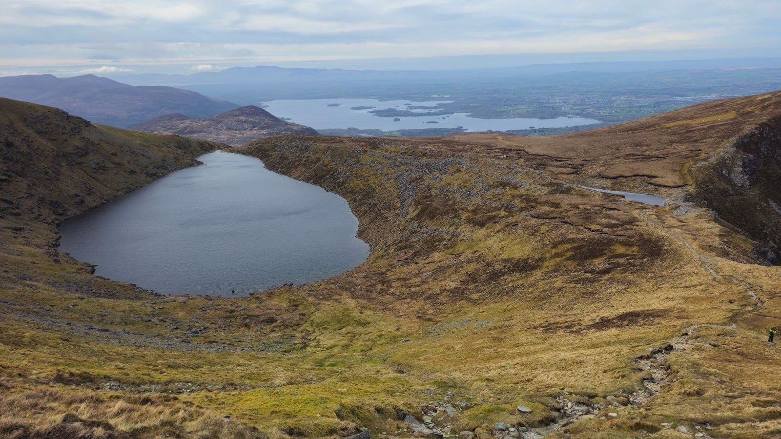 The Devil's Punchbowl corrie lake on Mangerton Mountain with views stretching toward the Lakes of Killarney in Killarney National Park.
