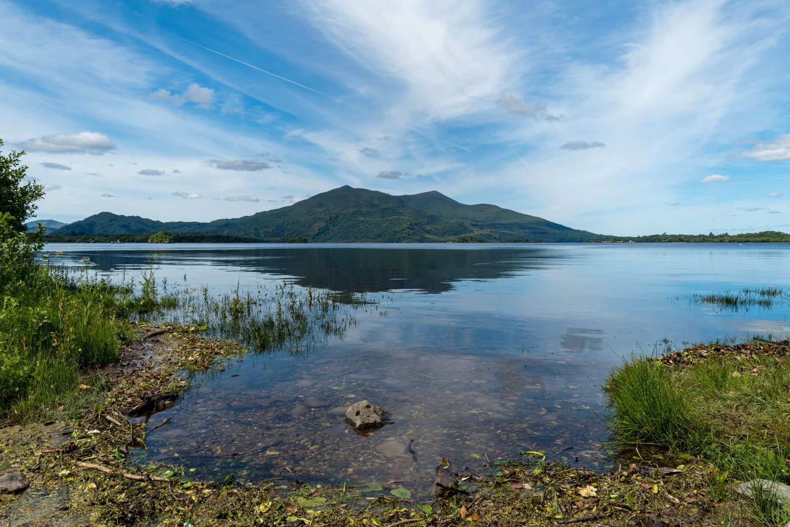 Calm waters of Lough Leane reflecting mountains and blue skies in Killarney National Park.