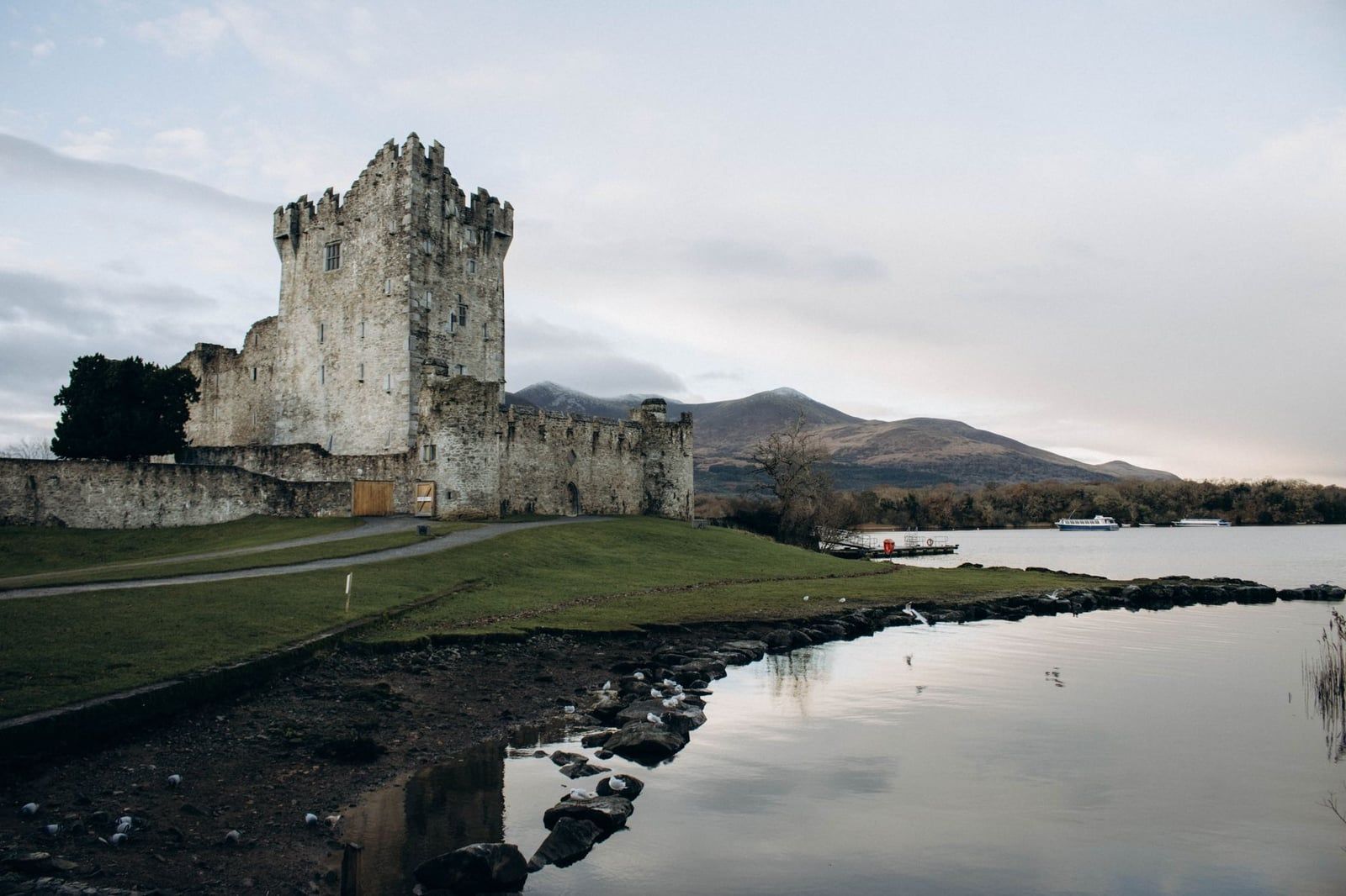 La tour en pierre et les murs du château de Ross s'élèvent le long de la rive de Lough Leane sous des montagnes saupoudrées de neige dans le parc national de Killarney.